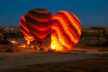 Sıcak hava balonları Kapadokya 'da güneş doğarken uçmaya hazırlanıyor. Sıcak hava balonlarına sıcak hava üflüyor.. 