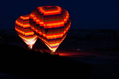 Sıcak hava balonları Kapadokya 'da güneş doğarken uçmaya hazırlanıyor. Sıcak hava balonlarına sıcak hava üflüyor.. 