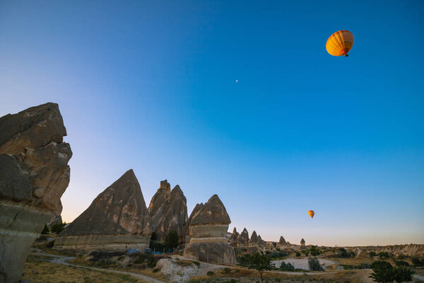 Fairy Chimneys and Hot Air Balloons in Cappadocia Turkey. Beautiful hot air balloon background photo with peri bacalari in Goreme Town.
