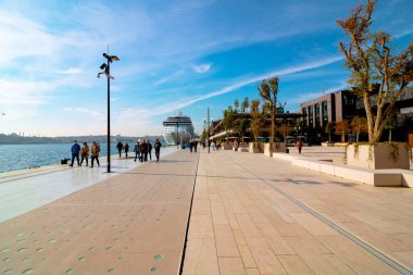 Galataport İstanbul. Yürüyen insanlarla Galataport 'un geniş açılı görüntüsü ve arka planda bir yolcu gemisi. İstanbul Türkiye - 11.13.2021