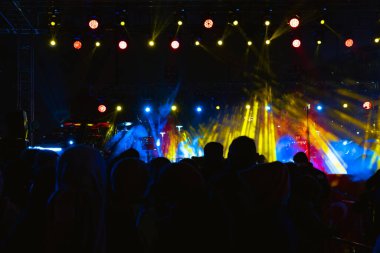 Konser arkaplanı. Sahnedeki spot ışıkları ve gece konserindeki insanların silueti.. 