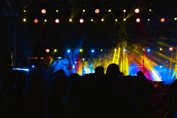 Fondo del concierto. Proyectores en el escenario y silueta de personas en concierto — Foto de Stock