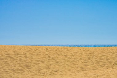 Kumsal. Arka planda açık gökyüzü olan deniz ve ayak izleri olan sahil. Yaz tatili arka plan fotoğrafı.