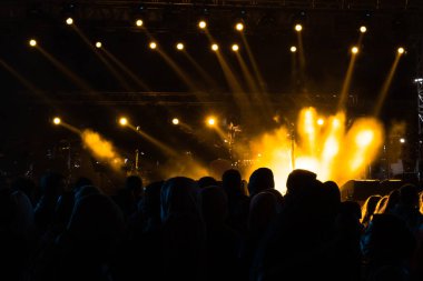 Concert background. Yellow spotlights on the stage and silhouette of people. Concert or event background photo. Noise effect included.