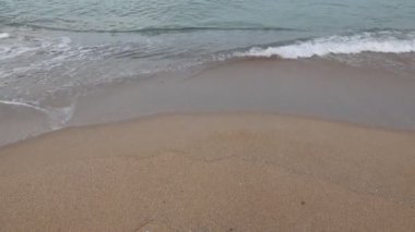 Waves breaking on the beach. Wavy calm sea and sandy beach.