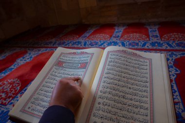 Kutsal Kuran 'ı okuyorum. Camide Kuran okuyan Müslüman bir adam. Kur 'an' dan bölümler, Ya 'cizeler ve (Allah tarafından) yazılmış sahifeler. İslam veya ramazan arkaplan fotoğrafı. 