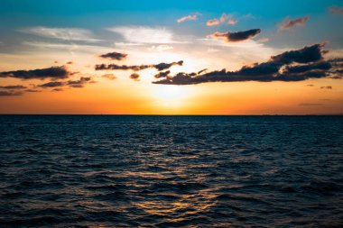 Denizin üzerinde gün batımı. Bulutların siluetiyle gün batımı fotoğrafı. Dramatik bulutlar ve karamsar deniz.