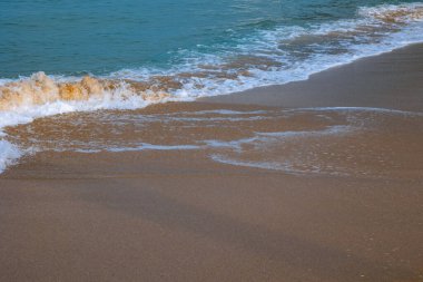 Dalgalar kopuyor. Dalgalar ve bir insanın gölgesi olan kumlu plajlar. Tatil veya tatil konsepti geçmişi.