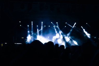 Sahnedeki spot ışıkları. Konserdeki insanların silueti. Gürültü dahil.