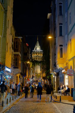 İstanbul gecesi. Galata Kulesi ve geceleri sokaktaki insanlar. İstanbul Türkiye - 10.15.2021