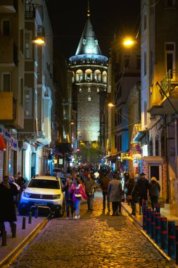 Galata Tower and people in the street at night. Travel to Istanbul background. Noise included. Istanbul Turkey - 10.15.2021