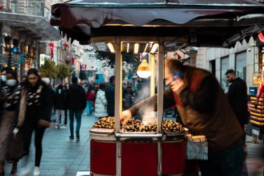 İstiklal Caddesi 'nde ya da İstanbul' da İstiklal Caddesi 'nde kavrulmuş kestane arabası. Türk sokak yemekleri. İstanbul Türkiye - 12.28.2021