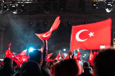 İnsanlar gece konser alanında Türk Bayrakları sallıyor. Türkiye konsept fotoğraflarının ulusal günleri ya da bayramları. Ses efektli bulanık fotoğraf.