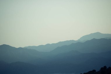Gün batımında dağları ya da tepeleri kaplayan katmanlı bir orman. Doğa fotoğrafı. Gün batımında tepeler ya da gün doğumunda siluetler ya da gölgelerle. Alıntı arka plan kavramı. 