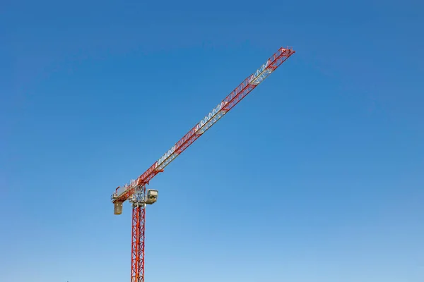 Tower crane. A red and white colored tower crane in construction site isolated on clear sky background with copy space for text. Construction background photo.