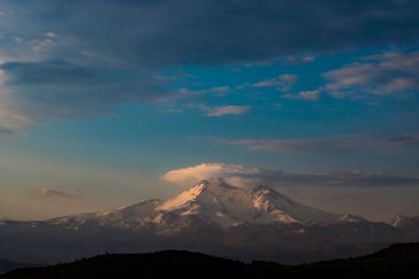 Sabahları bulutlar ve karlı tepelerle dolu bir dağ. Kayseri Türkiye 'deki Erciyes Dağı. Arkaplan konsepti fotoğrafından alıntı.