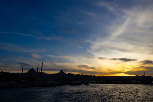 Istanbul silhouette at sunset from a ferry. Cityscape of Istanbul with Eminonu District and Galata Bridge.