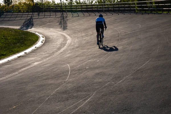 Biker training or exercising on the cycle-racing track in the park. Healthy lifestyle or biking or hobby concept photo.