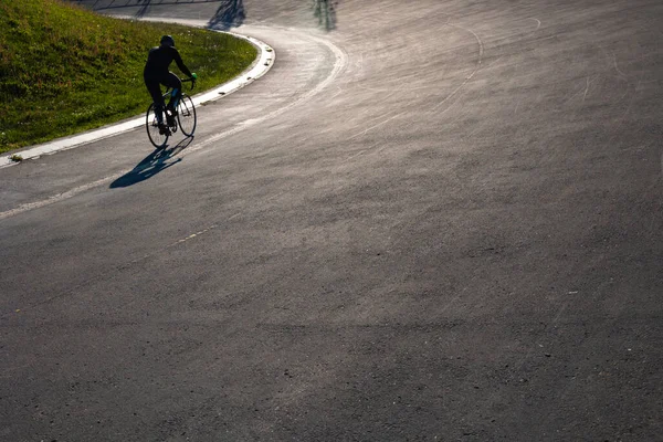 Silhouette of a biker on the cycle-racing track in the park. Healthy lifestyle background photo.