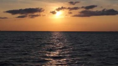 Bir tekne ya da gemiden parçalı bulutlu gökyüzü ile deniz ya da okyanus üzerinde gün batımı. El kamerasının etkisi. Gün batımında tekne ya da gemi turu. Deniz arka planında dramatik bir sahne.