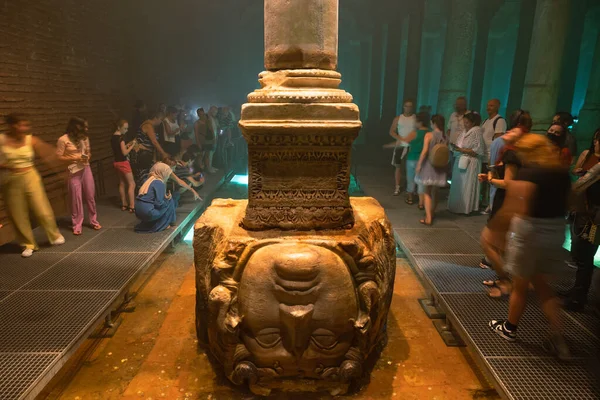Tourists and the Medusa Head Pillar in Basilica Cistern or Yerebatan Sarnici. Travel to Istanbul background photo. Noise and grain included. Selective focus. Istanbul Turkey - 8.3.2022