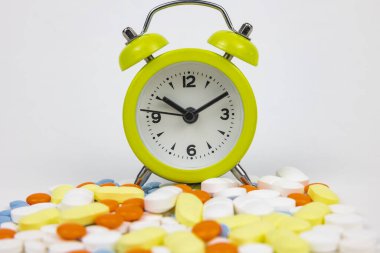 Alarm clock with pills. Using medicines in right time concept photo. Using medical drugs or medicines or pills in time.
