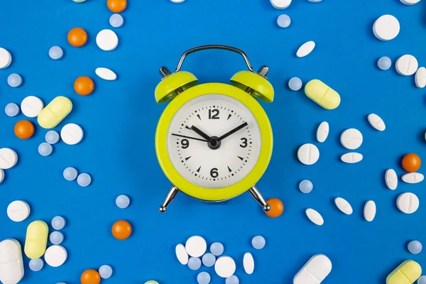 Medical pills with alarm clock. Taking pills or capsules on time concept photo. Remembering to take drugs.