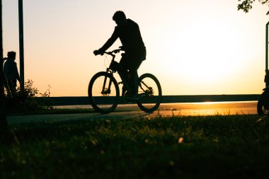 Silhouette of a biker in the park. Biking at sunset. Healthy lifestyle concept. Bicyclist riding a bike in the park.