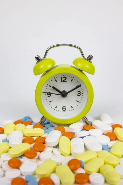 Taking pills or medical drugs on time background photo. Pills and a clock in vertical view. Using medicine vertical story background photo.