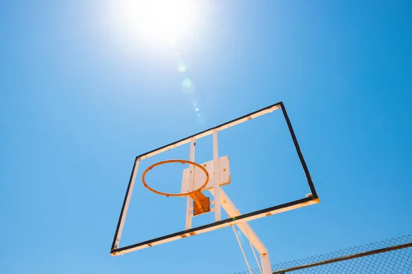 Broken backboard of basketball field in the park. Abandoned town concept photo. Sunlight and lensflare.