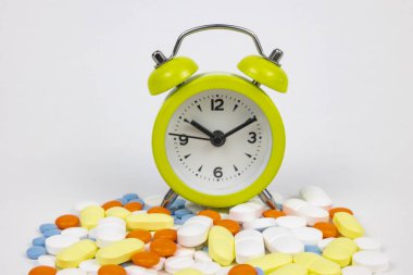 Using medicines in time concept. Clock on the pills isolated on white background. Medicine or health or healthcare background photo.