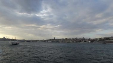 İstanbul manzarası bulutlu gökyüzü ile gün batımında bir feribottan. Galata Kulesi ve İstanbul şehir manzarası. İstanbul Türkiye - 3.30.2021