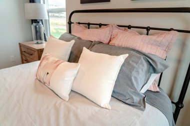 Yatak odasındaki siyah metal çerçeveli yumuşak yastıklar.