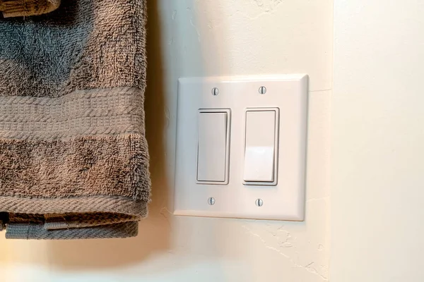 Light switch and hanging gray towel inside the bathroom of a home — Stock Photo, Image