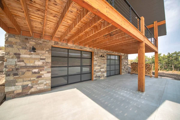 Нетиповий домашній гараж зовні з кам'яними стінами і подвійними скляними гаражними дверима — стокове фото