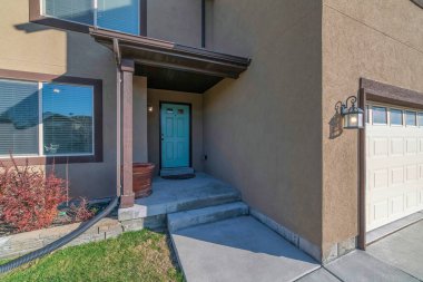 Nane yeşili ön kapısı ve garajı olan bir evin dışı.