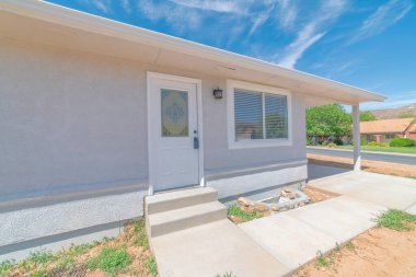 Beyaz kapısı ve bodrum penceresi olan bir evin dışında.