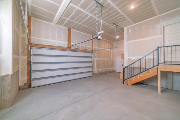 Interiör i ett oavslutat garage med automatisk vit sektionsdörr — Stockfoto