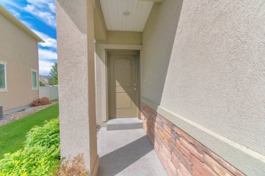 Kahverengi kremalı ön kapısı olan evin dar giriş yolu.