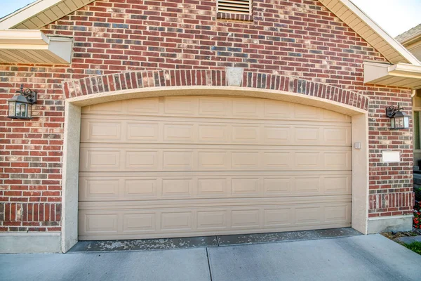 Arched beige puerta de garaje seccional de una casa con dos lámparas de pared en el lado — Foto de Stock