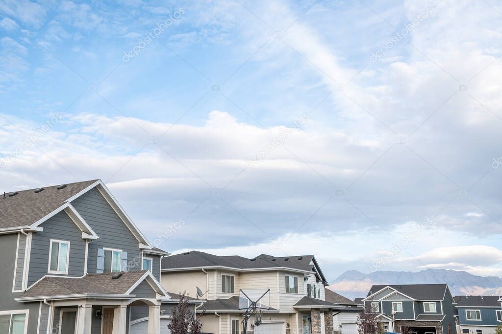 Bright cloudy sky above the residential area against the mountains at the background
