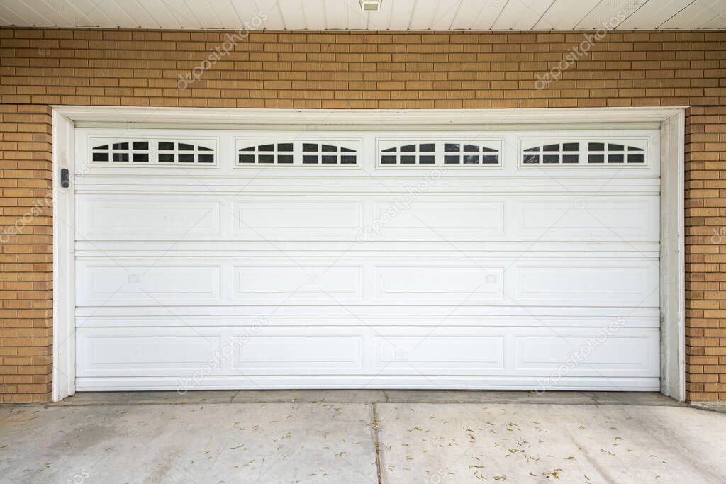 White sectional garage door with window panels and concrete driveway