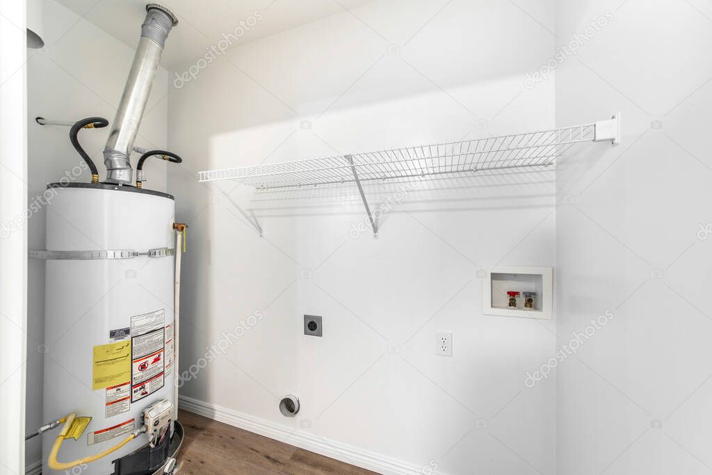 Empty white laundry room with water heater tank and wall mounted wire shelf