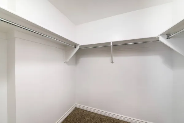 Белые полки с деревянными кронштейнами и металлическими стержнями внутри прогулки в шкафу — стоковое фото