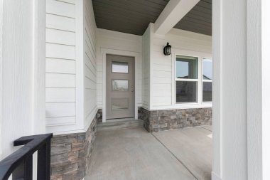 Parmaklıklar, beyaz vinil ahşap ve taş kaplamalı dış giriş.