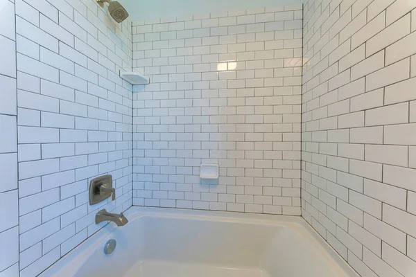 Alcove bathtub with white subway tile surround with black grout