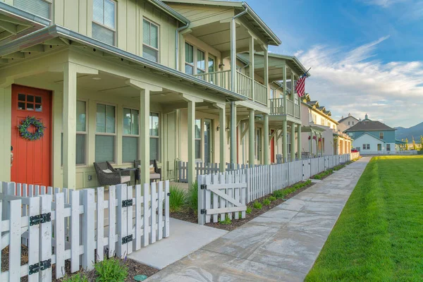 Apartment complex with light green siding and white picket fence at Daybreak, Utah