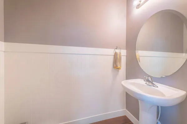 Раковина с подвешенным полотенцем на боку и овальным зеркалом в маленькой ванной — стоковое фото