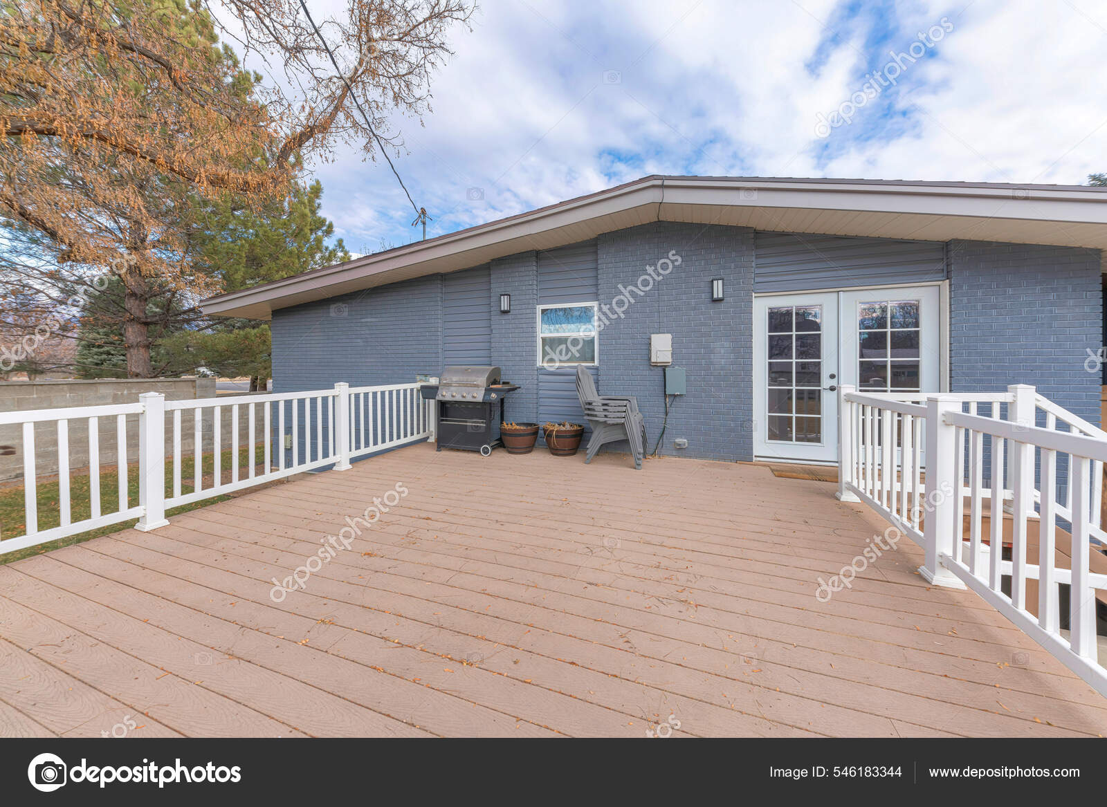 Deck of a gray house with a wood planks flooring and white railings