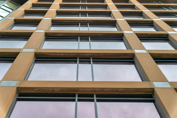 Vista de ángulo bajo de un edificio con revestimientos de pared marrón y ventanas de vidrio teñido — Foto de Stock